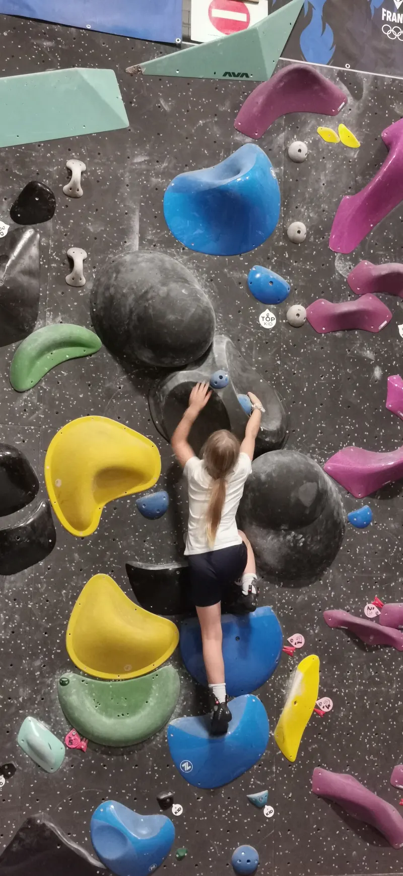 Une enfant grimpe sur le mur de bloc